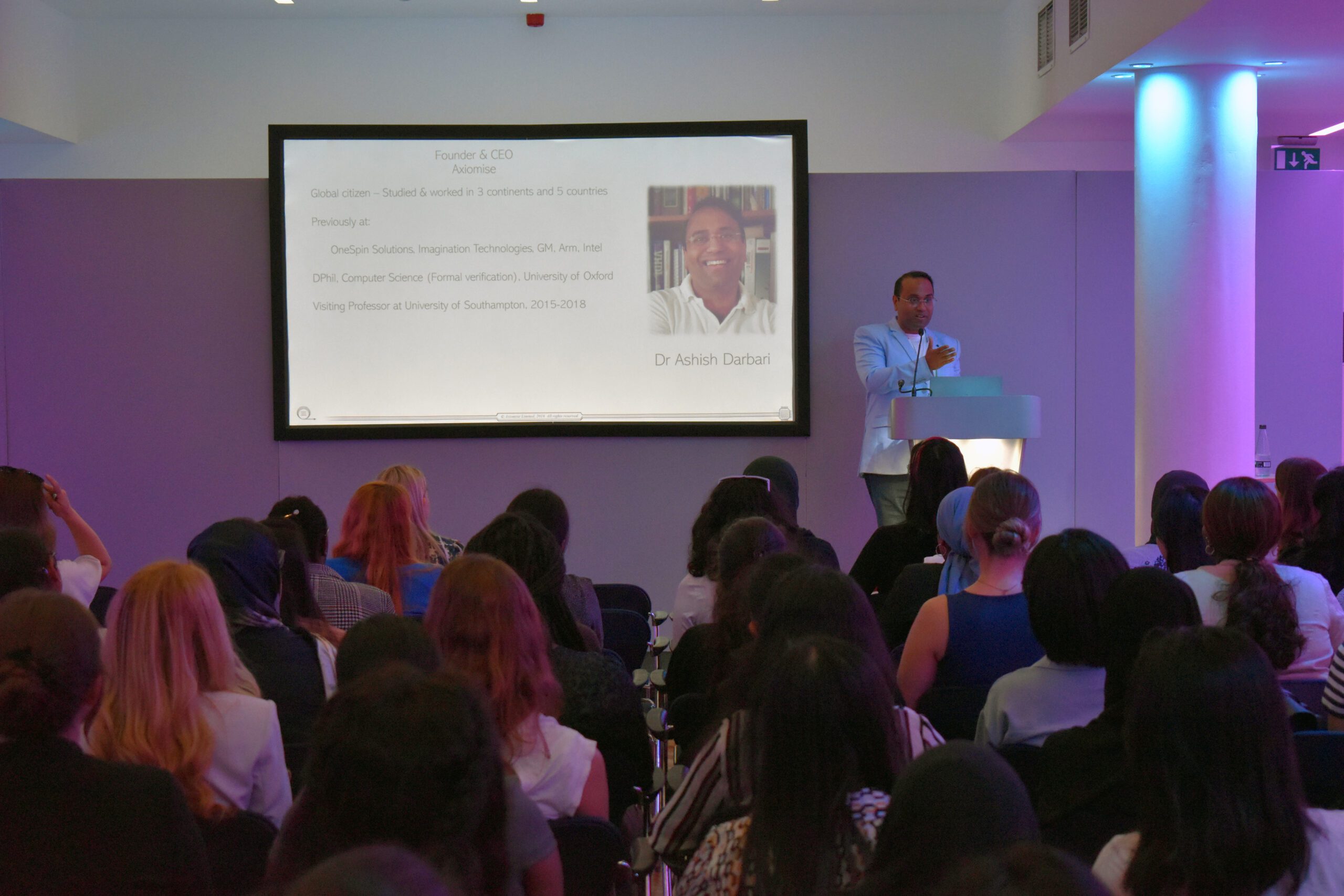 A male speaker talking in a theatre with rows of attendees