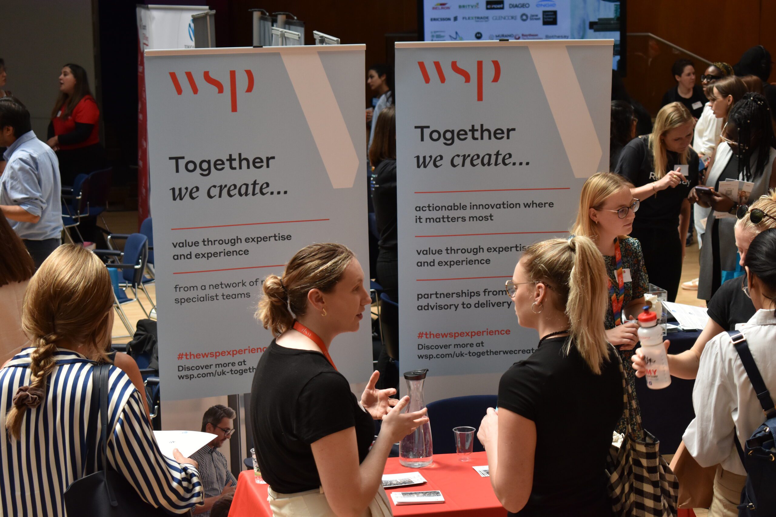 Employers networking with students in front of a company banner